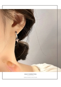 Close-up of elegant silver hoop earrings with heart-shaped pink zircon pendants on ear