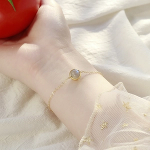 Minimalist gold chain bracelet with a round translucent gemstone shown on model's wrist