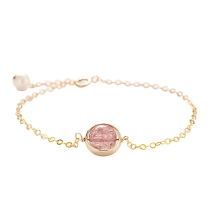 Golden strawberry crystal bracelet with a white pearl on a clean minimalist white backdrop