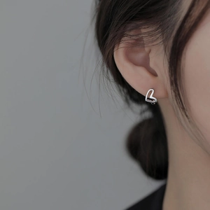 Elegant hollow heart-shaped silver earrings worn by a model for a minimalist jewelry look