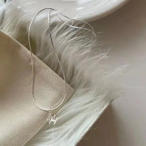 Vue détaillée du pendentif lettre H argenté sur une chaîne fine au fini poli miroir
