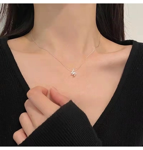 Gros plan d'un collier avec pendentif lettre H en argent sur le décolleté d'une femme