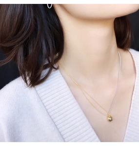 Detailed view of bicolor gold and silver chain necklace with a polished gold sphere pendant