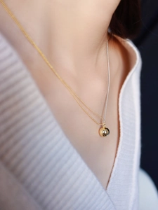 Detail of minimalist dual-tone gold and silver beaded chain with polished ball pendant