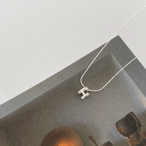Vue détaillée du pendentif lettre H en argent sur une chaîne fine de style serpent