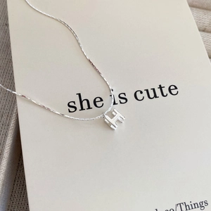 Vue macro du collier avec pendentif H argenté, chaîne fine et détails de luxe