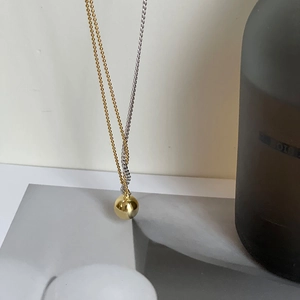 Minimalist gold and silver mixed chain necklace with a polished gold ball pendant