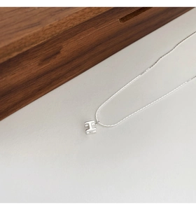 Gros plan du pendentif 3D en forme de H argenté poli avec une chaîne minimaliste