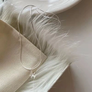 Collier élégant avec pendentif lettre H en argent pour femme sur plume et lin blanc