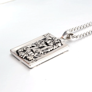 Macro detail of vintage silver stainless steel King K card pendant with skull design