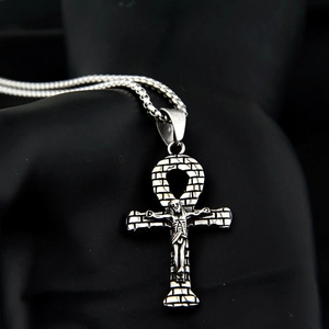 Dettaglio del ciondolo croce Ankh con rilievo di Gesù e trama a mattoni sulla collana