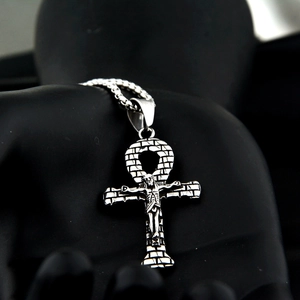 Dettaglio del ciondolo a croce Ankh d'argento con figura di Gesù e trama a mattoni