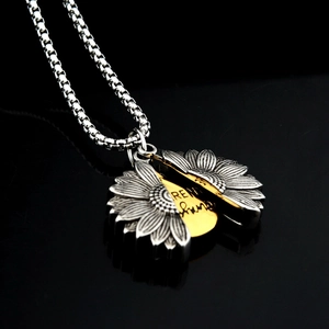 Gros plan du pendentif tournesol s'ouvrant sur le message gravé You Are My Sunshine