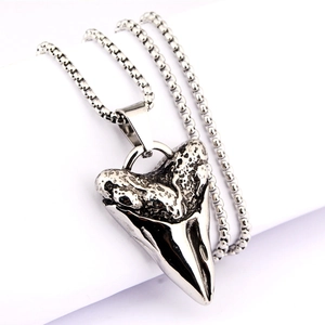 Dettaglio del ciondolo a dente di squalo con trama antica e finitura in metallo lucido