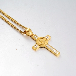 Detailed close-up of a gold-plated cross pendant with baguette-cut zircons and medal