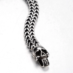 Détail macro d'une chaîne en maille épi avec tête de mort réaliste en acier vintage