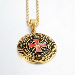 Détail macro du pendentif en or avec émail rouge, épées et gravure latine
