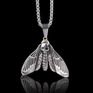 Gros plan d'un pendentif papillon tête de mort argenté vintage avec chaîne à billes