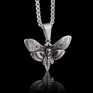 Détail du pendentif tête de mort et papillon argenté avec gravure fine sur une chaîne