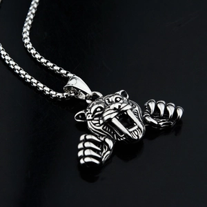 Vue macro d'un pendentif tigre à dents de sabre en acier argenté sur chaîne box