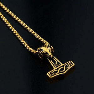 Detail of golden Thor's Hammer Mjölnir pendant with ram head and Celtic knot patterns