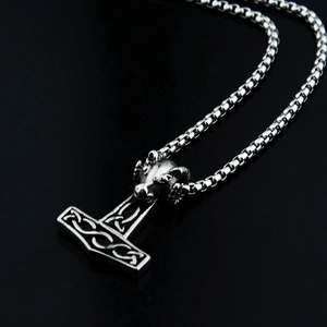 Detailed view of silver Thor's Hammer pendant with ram head engraving and pearl chain