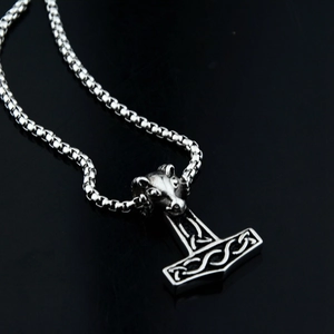 Macro detail of Viking Mjolnir pendant with ram skull and Celtic knot engravings