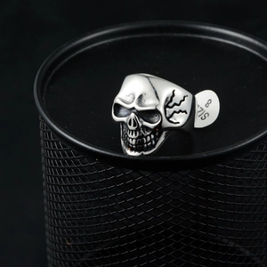 Close-up of punk skull ring in silver steel with size 8 tag on a black mesh surface