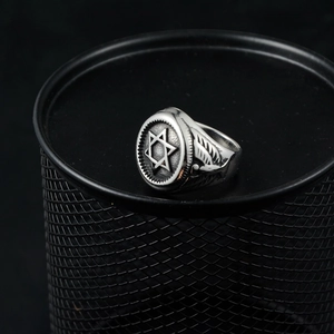 Bague vintage argentée avec hexagramme et ailes d'aigle sur un socle métallique noir