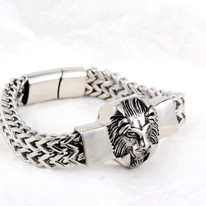 Makroansicht des fein gravierten Löwenkopf-Anhängers an einem silbernen Gliederarmband