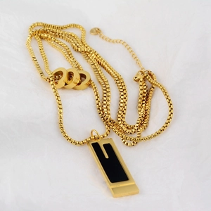 Detail of gold box chain necklace featuring black rectangular pendant and triple rings