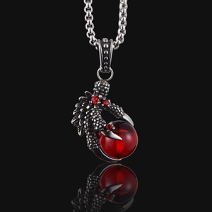 Detailed view of punk dragon claw pendant with red gemstone and oxidized steel texture