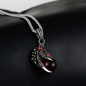 Macro view of vintage silver dragon claw pendant with red stone on black leather background