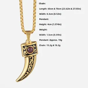 Detail of gold wolf tooth pendant with red gemstone and black vintage totem patterns