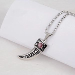 Close-up of vintage wolf fang pendant with black enamel patterns and purple gemstone inlay