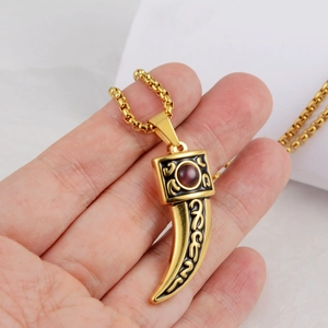 Close-up of golden wolf tooth pendant with purple gemstone and black etched details