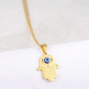 Macro view of gold Hamsa hand pendant featuring a blue evil eye and sparkling rhinestones