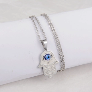 Macro shot of silver Hamsa hand pendant with blue evil eye and sparkling zircon details