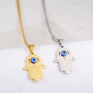 Detail of Hamsa Hand pendants in gold and silver with blue Evil Eye and cubic zirconia