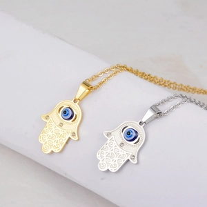 Detailed macro view of gold and silver Hamsa Hand pendants with blue evil eye accents