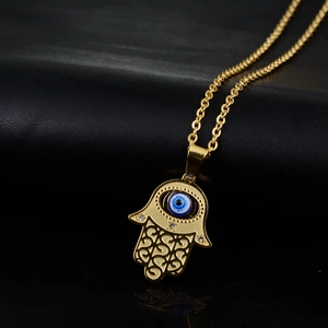 Macro detail of golden Hamsa Hand pendant with evil eye and intricate filigree patterns