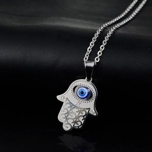 Macro detail of Hamsa Hand pendant with blue evil eye and sparkling crystals on steel chain