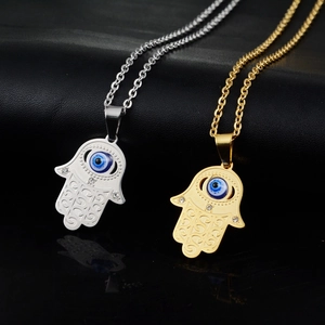 Gold and silver Hamsa Hand necklaces with evil eye pendant on black leather background
