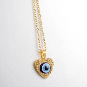 Detailed close-up of golden heart pendant with evil eye and sparkling rhinestones