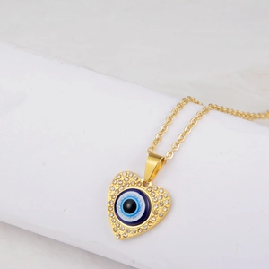 Macro detail of gold evil eye heart pendant with sparkling crystals on a cross chain