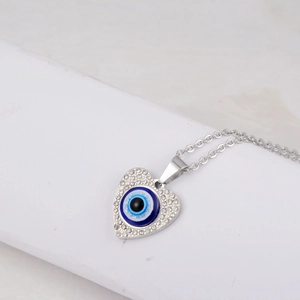 Close-up of a silver heart pendant featuring a blue evil eye and sparkling crystals