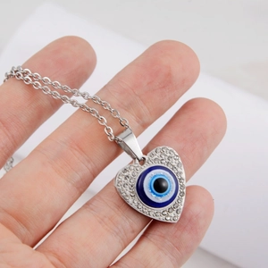 Macro detail of silver heart necklace with blue evil eye pendant and sparkling rhinestones