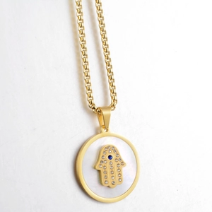 Detailed close-up of golden Hamsa hand pendant with blue gem and pearl base