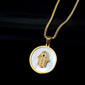 Detailed close-up of golden Hamsa Hand pendant with mother of pearl and blue evil eye