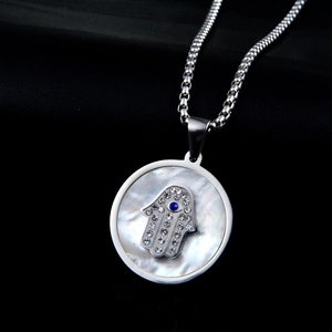 Macro view of Hamsa Hand pendant with white mother of pearl and blue evil eye detail